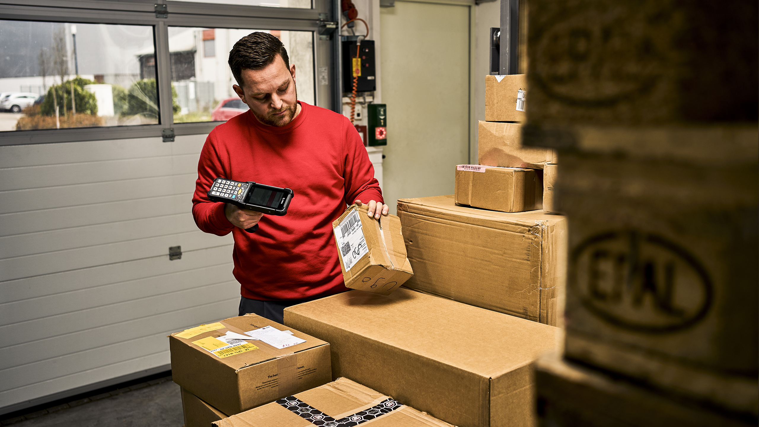 An employee in outgoing goods scans a stack of parcels