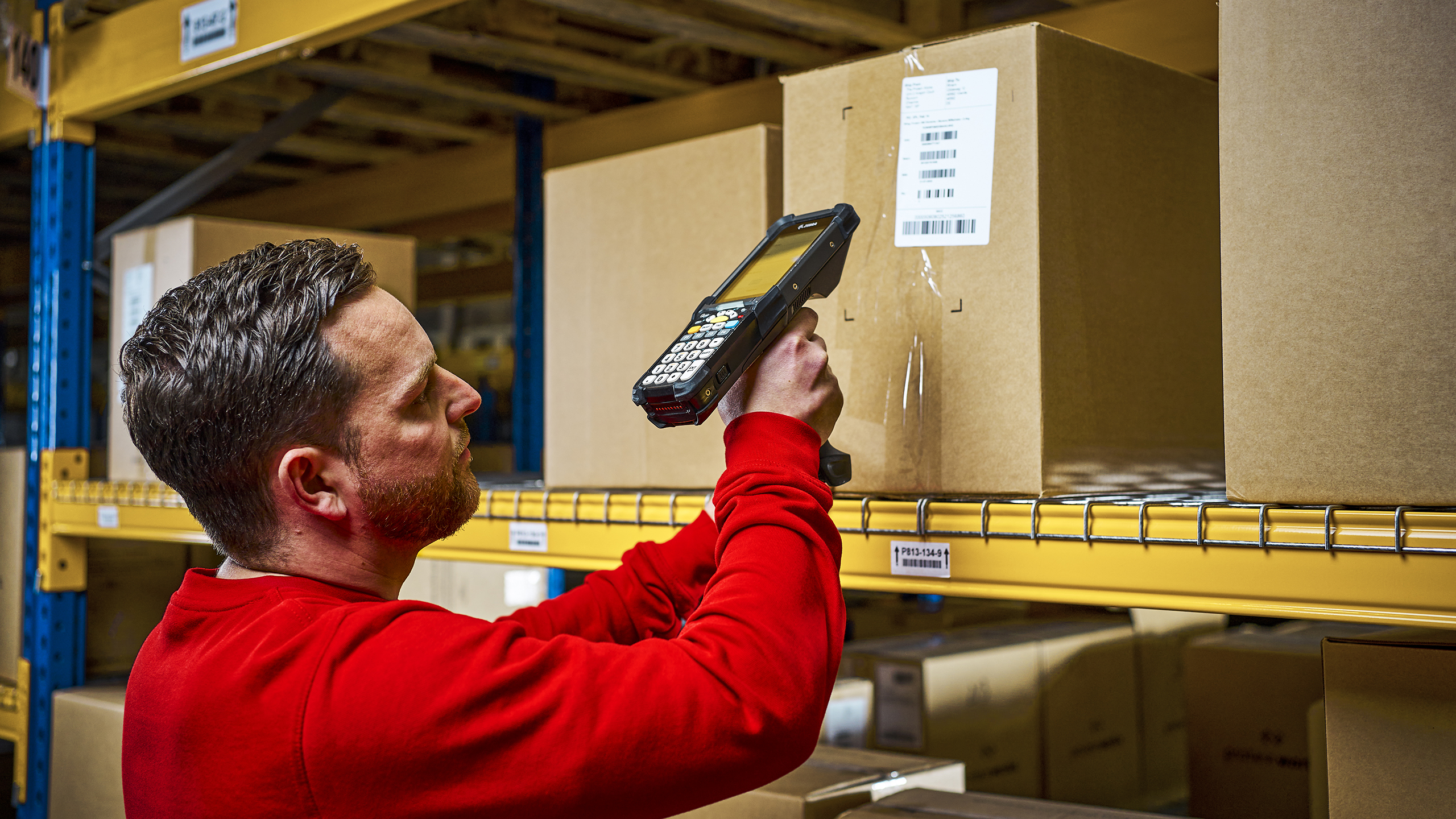 A picking employee of a fulfillment service provider scans a parcel in the high rack