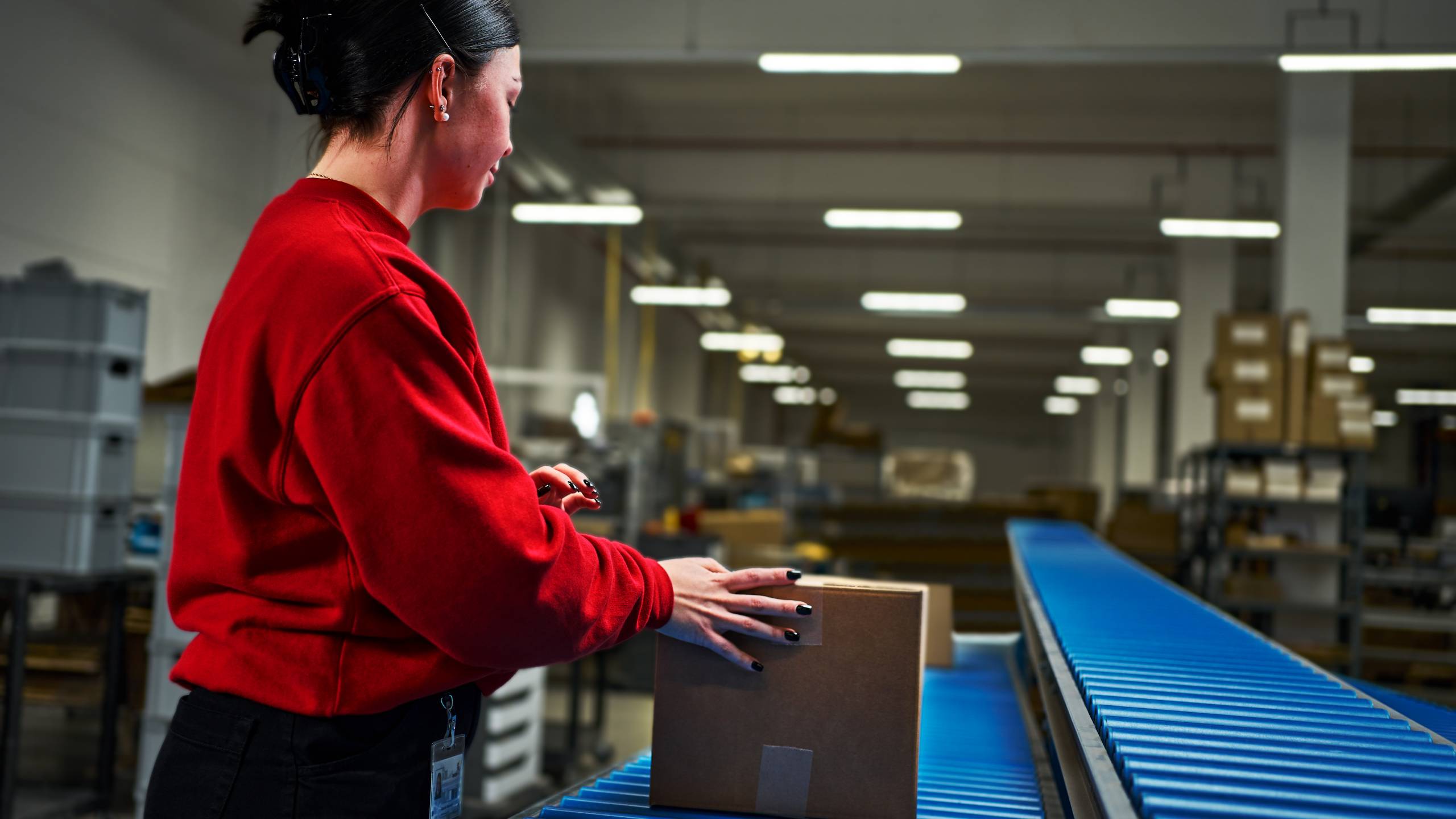 An employee in the dispatch department has finished packing an order and is now passing it on to the shipper