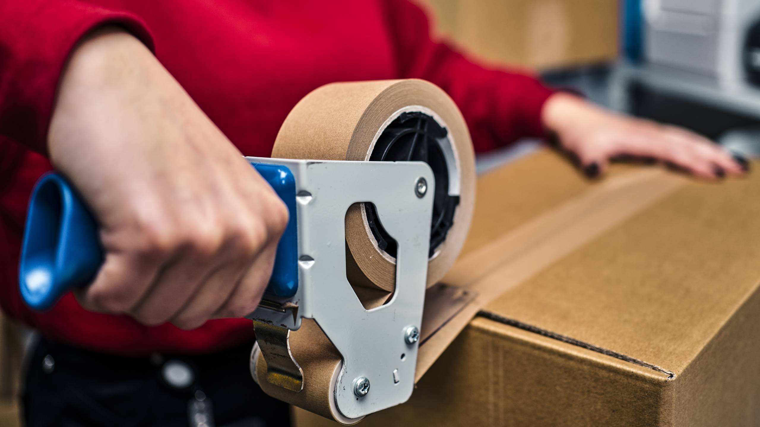 A shipping employee tapes up an order in a box so that the parcel can now be sent to the recipient.