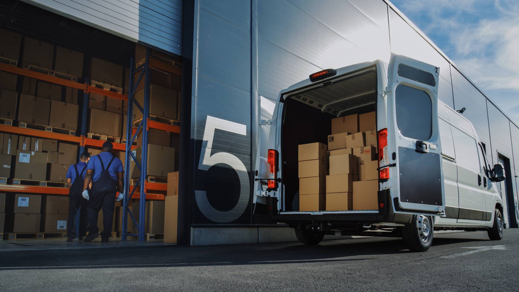 Ein Versandpartner lädt einen Teil der gepackten Pakete in einen Transporter