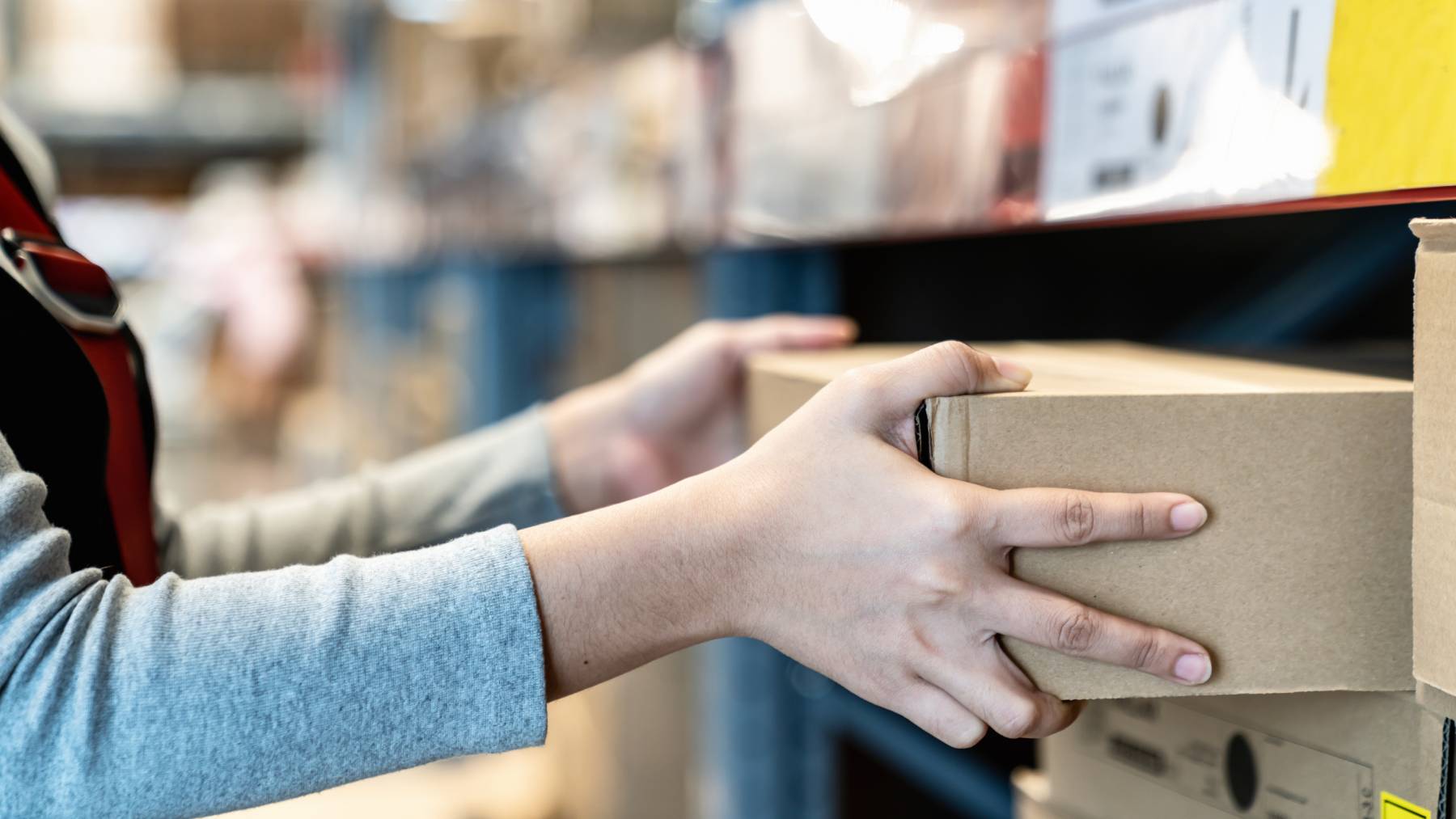 A woman takes a cardboard box from a shelf