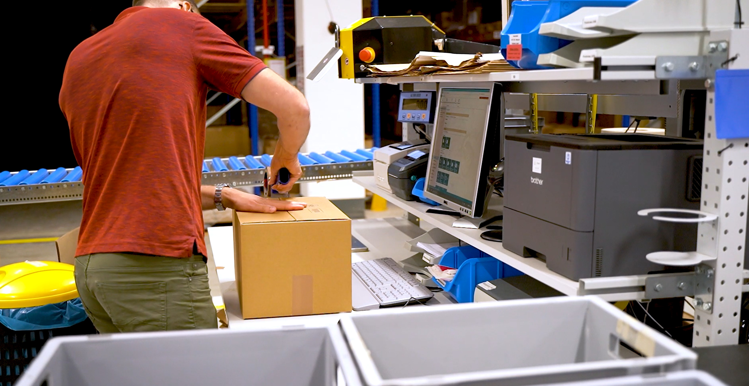 The picture shows a warehouse employee of a fulfillment service provider packing orders into a box at a packing table