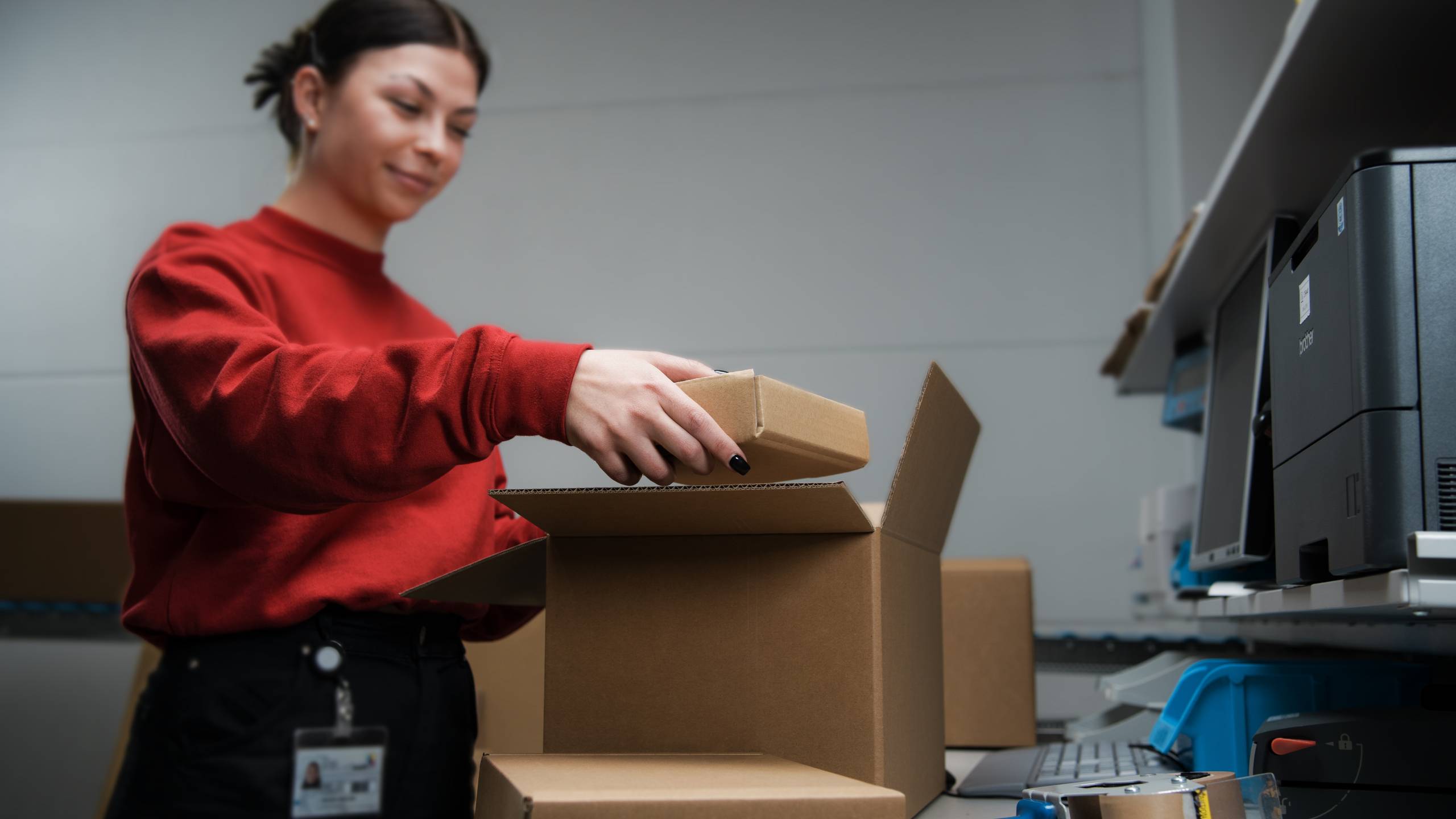 Eine Mitarbeiterin verpackt unterschiedlich grosse Pakete ineinander, so dass die Bestellungen einzeln und sicher verpackt werden können