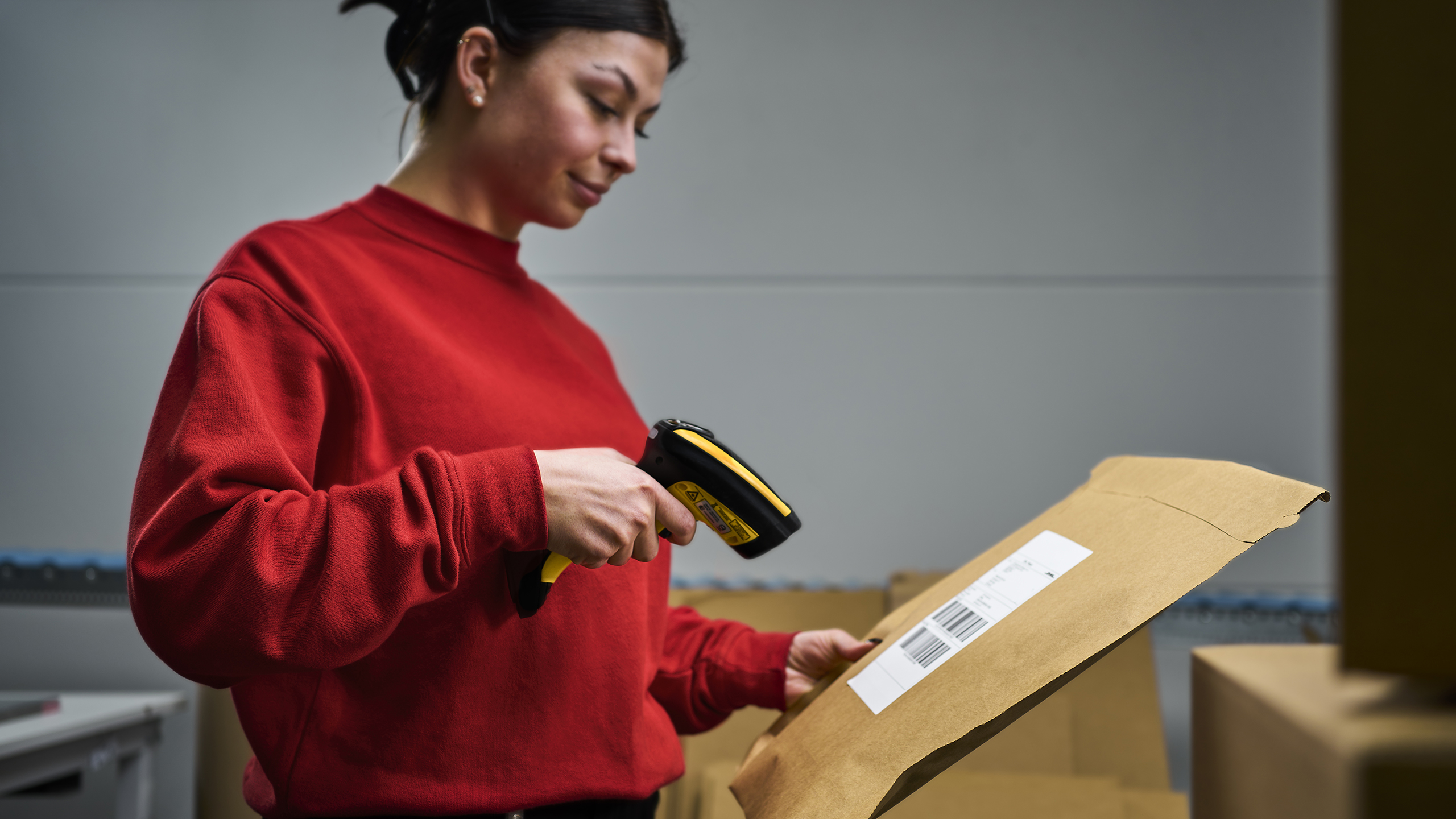 Eine Mitarbeiterin scannt eine gepackte Bestellung mit einem Handscanner