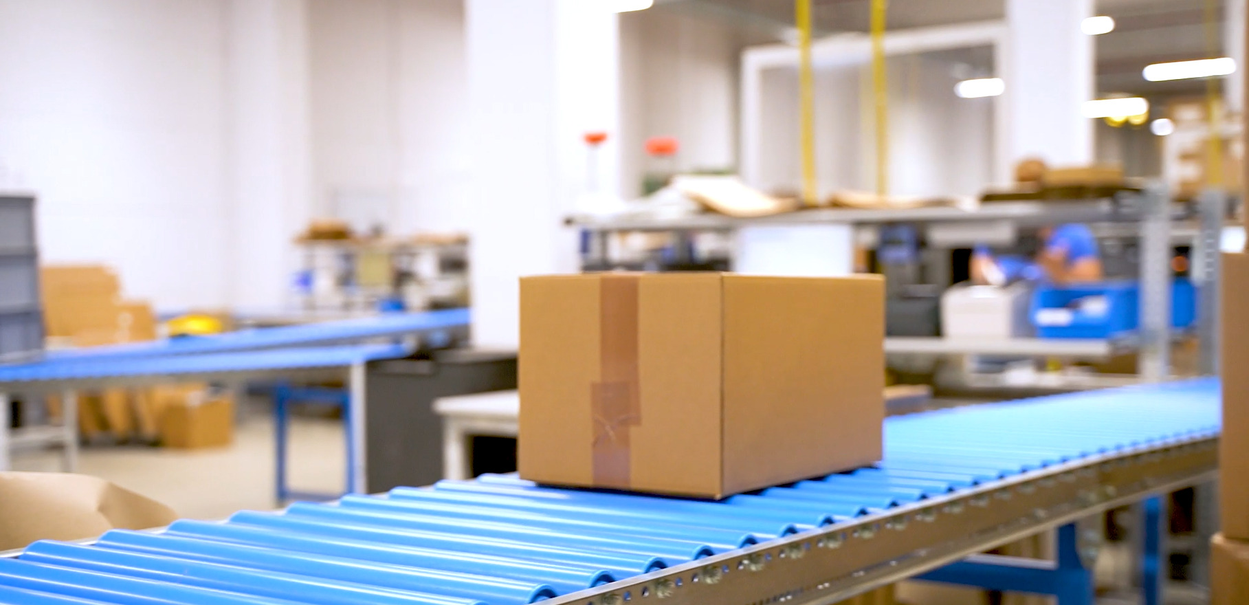 A fully packed shipping carton is transported on the conveyor belt to the outgoing goods area